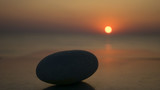 rock on the table and sunrise in the distance, at the seashore