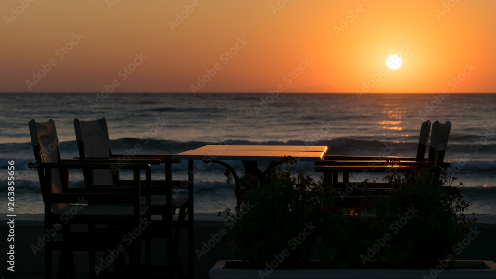 sunbathing on the beach with seating and dining table silhouette for breakfast and the sea with waves