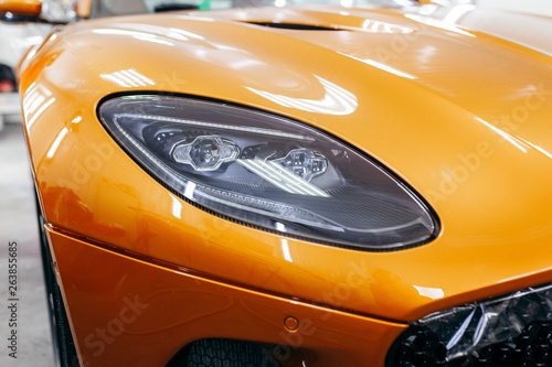 Orange modern car closeup on black background