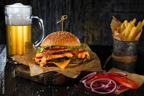 Delicious beef cheeseburger with  glass of beer , vegetables and lettuce, hand made, according to a classic recipe.