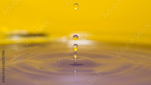 water splash in colorful background with a drop of water flying from above