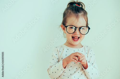 Portrait of cute beautidul cheerful little kid girl wearing in eyeglasses. Expression of baby. Childhood Emotions concepts. Happy child smiling. photo