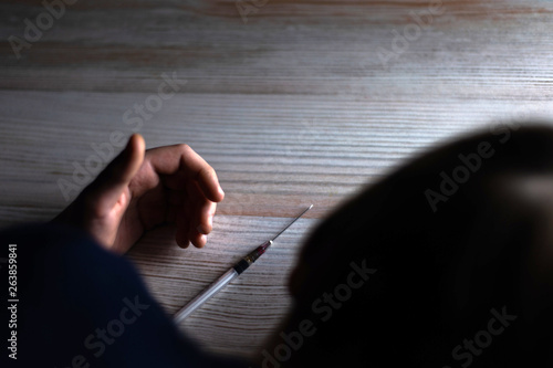 Wallpaper Mural heroin overdose: a syringe is lying next to the hand of a young guy on the table Torontodigital.ca