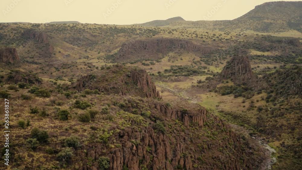 Golden light over a rocky canyon covered in vegetation and stream running below, slow motion 24 fps. Golden light over a rocky canyon covered in vegetation and stream running below, slow motion 24 fps.