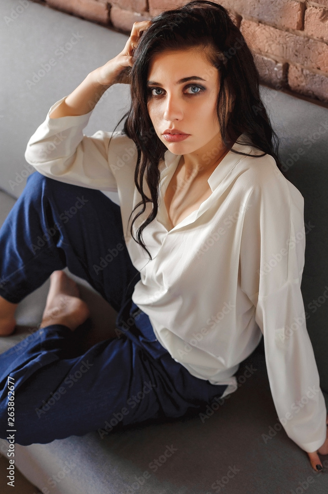 Naklejka premium sexy girl in a blouse and jeans on the couch