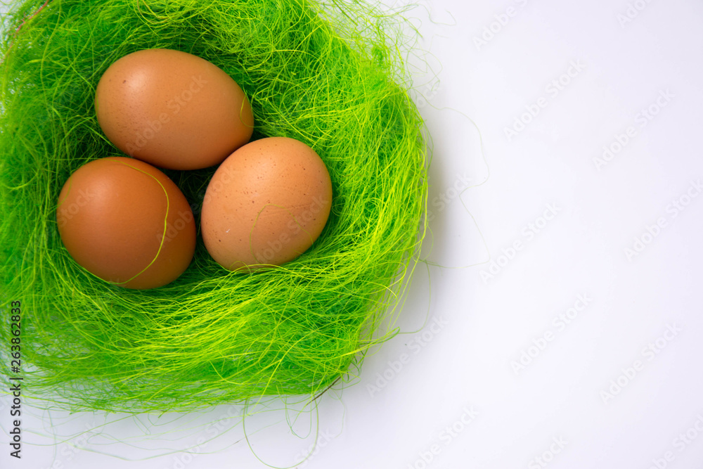 Green nest with three Easter eggs decoration - Easter concept, holiday tradition top view, close-up with copy space for text on white background Green nest with three Easter eggs decoration - Easter concept, holiday tradition top view, close-up with copy space for text on white background