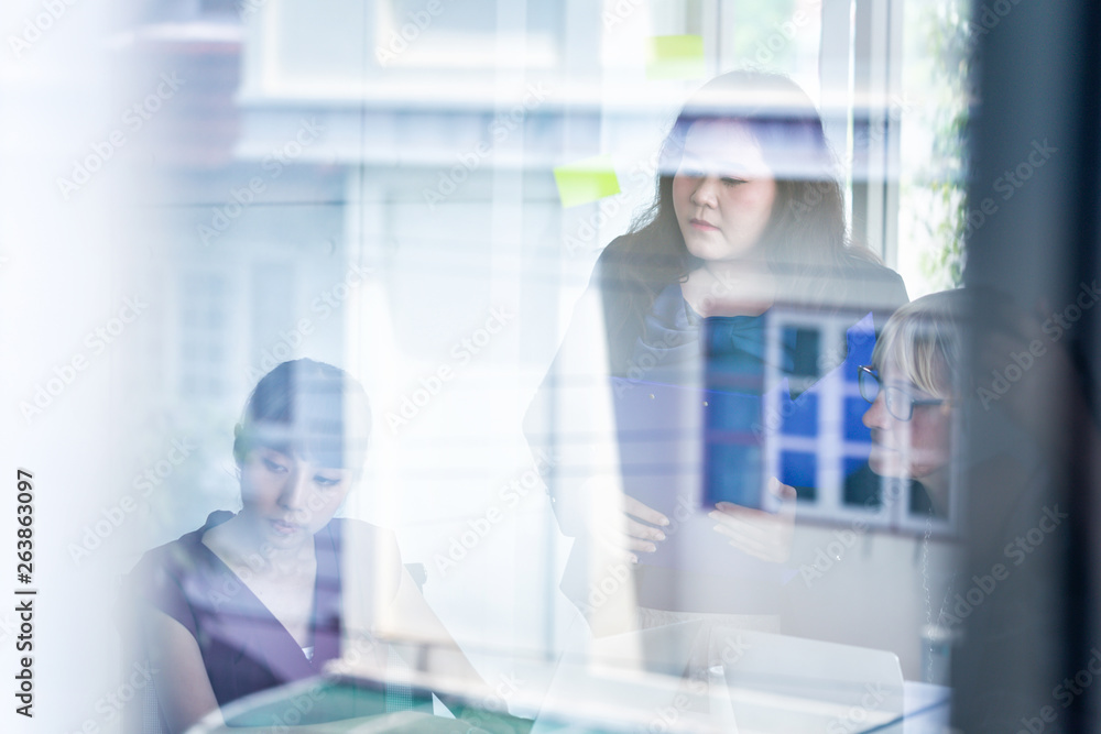 Group of Asian and Caucasian diverse businesswomen holding documents with glass reflection of office building Group of Asian and Caucasian diverse businesswomen holding documents with glass reflection of office building