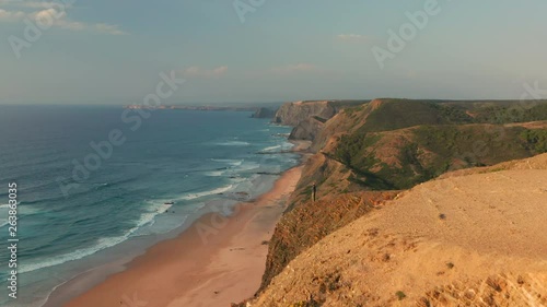 Aerial: A man standing on a viewpoint watching the surfers in Portugal. photo