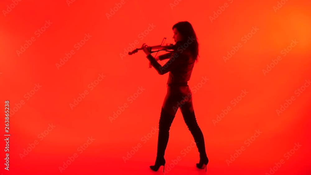 slim sensual young Asian girl in tight black leather clothes expressively plays the electric violin on a red background slim sensual young Asian girl in tight black leather clothes expressively plays the electric violin on a red background