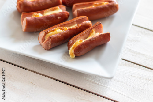 Roasted sausage with yellow cheese over white wooden background