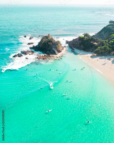 Photography Aerial shot at sunrise over the ocean and white sand beach with swimmers and sur