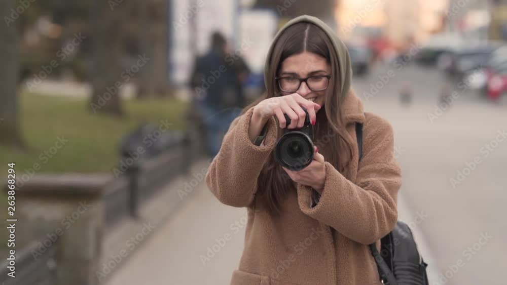 Beautiful photographer walks towards the camera as she takes pictures in a city. Beautiful photographer walks towards the camera as she takes pictures in a city.