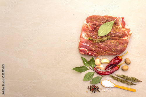 Raw pork shoulder. Spices, dry herbs, garlic, rosemary, bay leaf, hot pepper, nutmeg, pepper mix, salt. Ingredients for marinating meat. Stone background, top view, copy space.