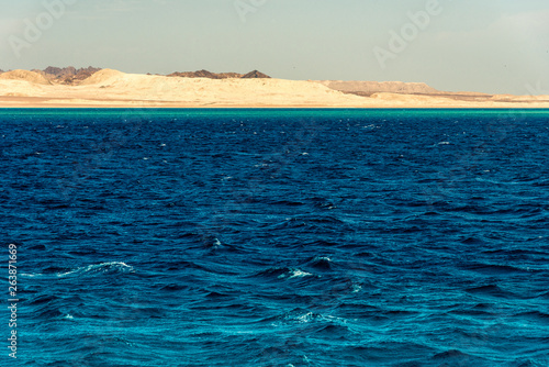 Seascape  view of the blue sea with high bald mountains in the background