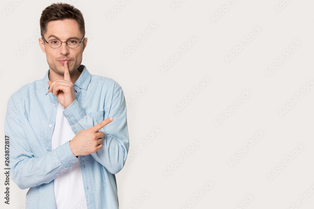 Man in glasses isolated on background shared secret point aside Man in glasses isolated on background shared secret point aside
