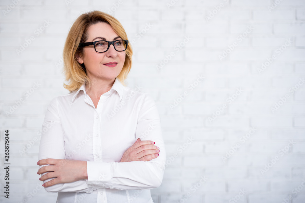 mature business woman in eyeglasses posing over white brick wall with copy space mature business woman in eyeglasses posing over white brick wall with copy space