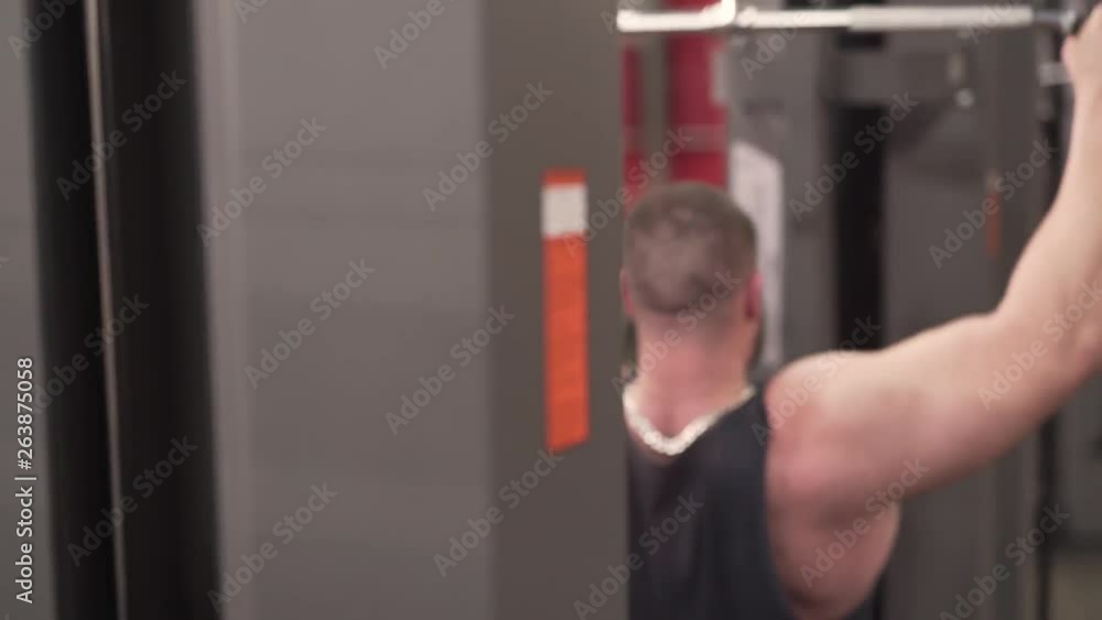 A back body part close up video of muscled sportsman from both left and right perspectives. There is a big tattoo on man's left shoulder. Background is blurred. He wears a black tank-top and a beard. A back body part close up video of muscled sportsman from both left and right perspectives. There is a big tattoo on man's left shoulder. Background is blurred. He wears a black tank-top and a beard.