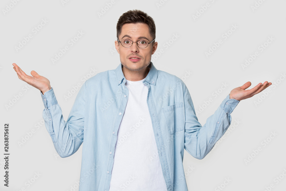 Puzzled Caucasian man in glasses shrug shoulders isolated on background