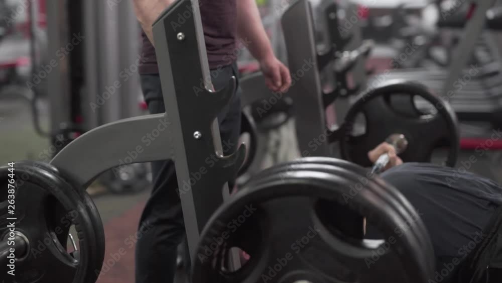 Strong Caucasian Male Bodybuilder Laying on Banch and Pulls Up Heavy Weights in Gym. Blurred Background Strong Caucasian Male Bodybuilder Laying on Banch and Pulls Up Heavy Weights in Gym. Blurred Background