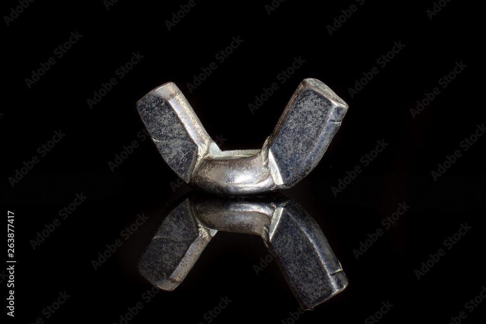 One whole metal wingnut work item isolated on black glass One whole metal wingnut work item isolated on black glass