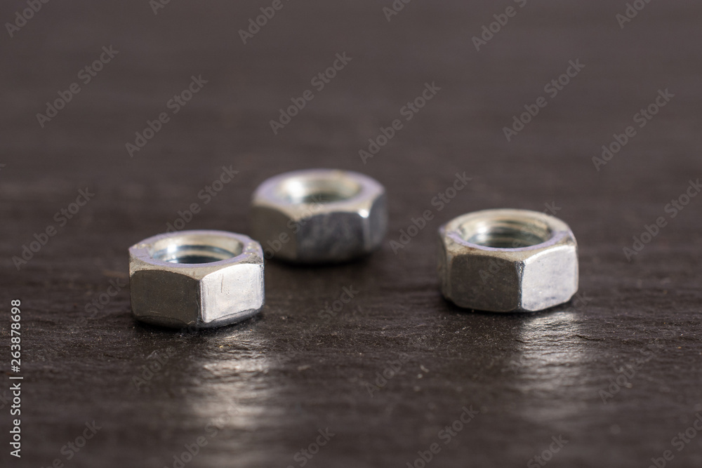 Group of three whole metal locking nuts work item on grey stone Group of three whole metal locking nuts work item on grey stone