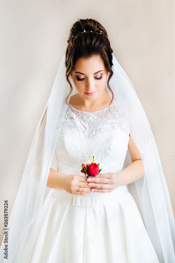 beautiful bride holds a boutonniere in her hands. bride on the b beautiful bride holds a boutonniere in her hands. bride on the b