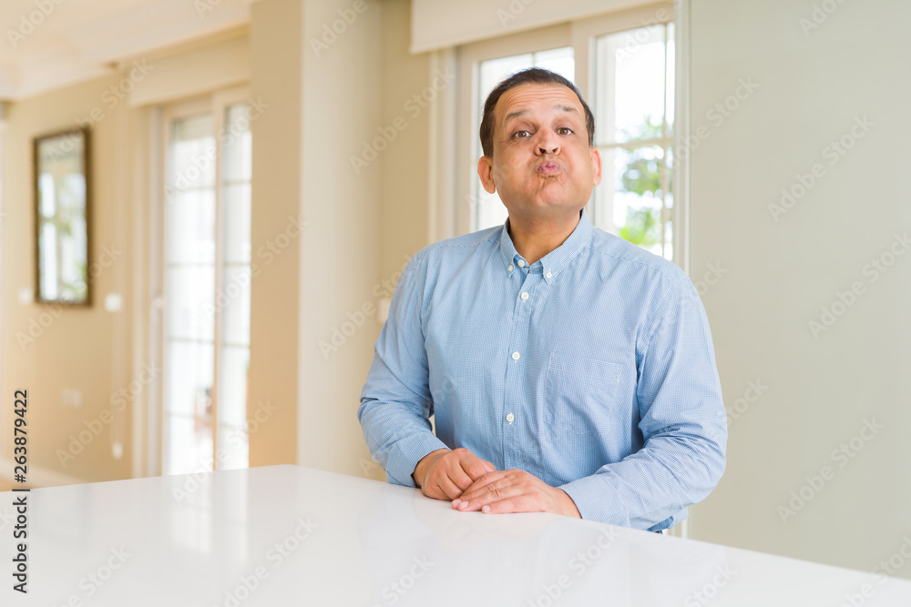 Middle age man sitting at home puffing cheeks with funny face. Mouth inflated with air, crazy expression. Middle age man sitting at home puffing cheeks with funny face. Mouth inflated with air, crazy expression.