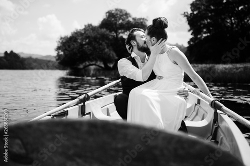 Black and white photo of bride and groom kissing in a rowing boat