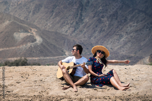 Couple singing and playing guitar buy the beach