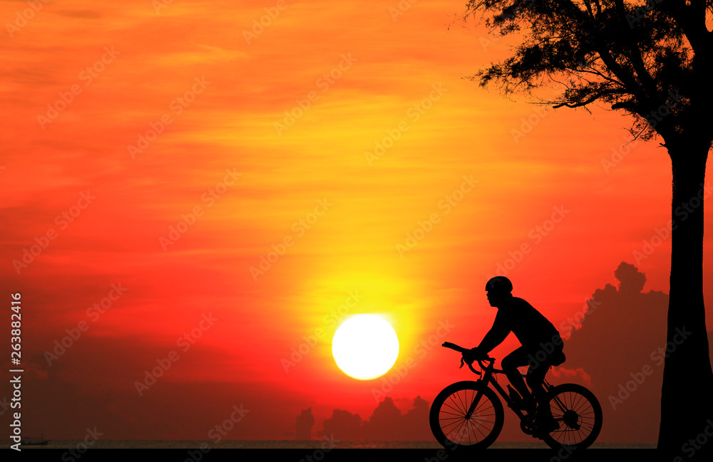 Fototapeta premium Silhouette man and bike relaxing on blurry sunrise sky background.