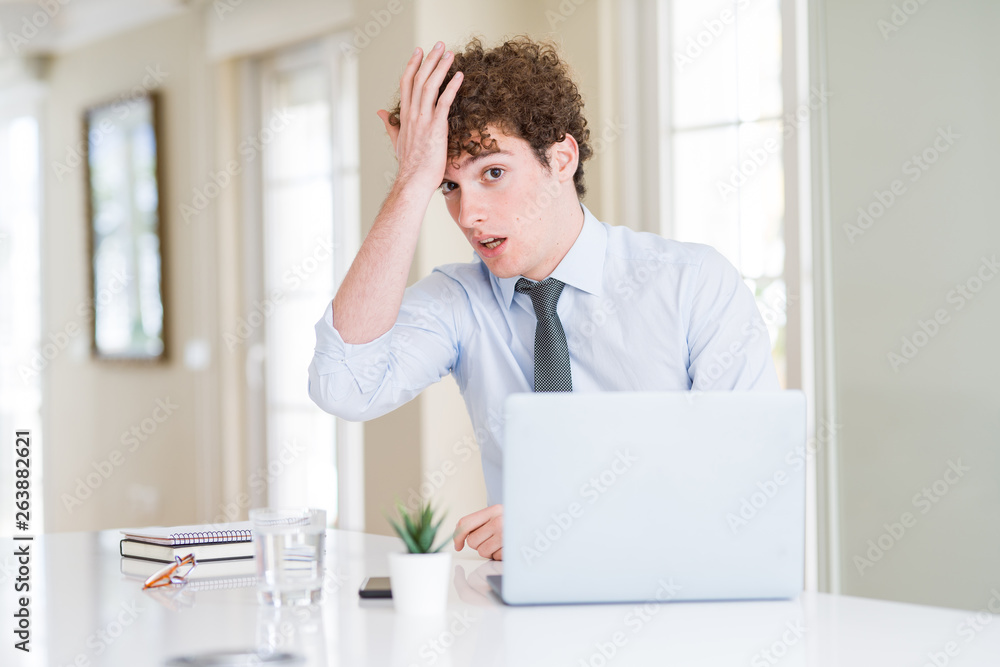 Young business man working with computer laptop at the office surprised with hand on head for mistake, remember error. Forgot, bad memory concept. Young business man working with computer laptop at the office surprised with hand on head for mistake, remember error. Forgot, bad memory concept.