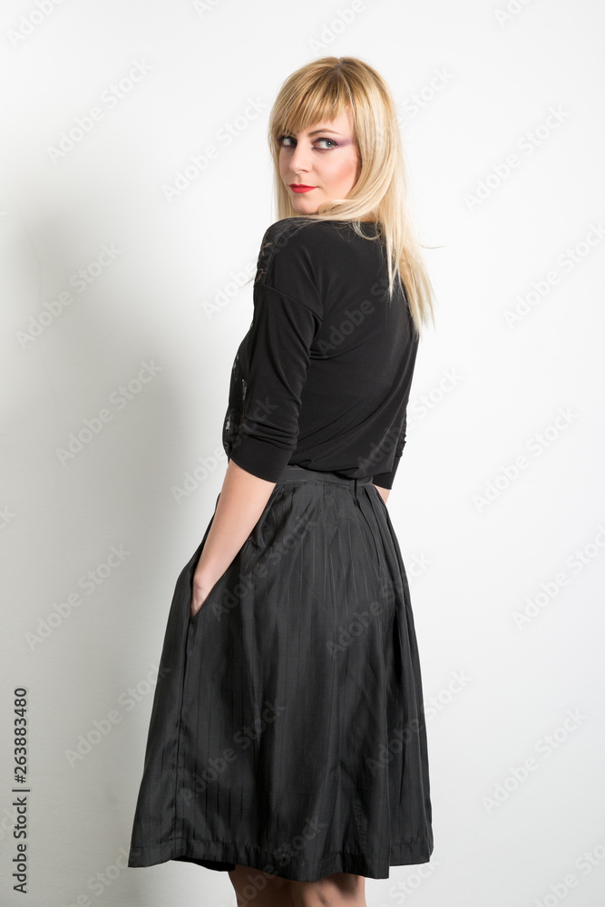 Attractive fashion indoor portrait of beautiful blonde girl posing in front of white wall Attractive fashion indoor portrait of beautiful blonde girl posing in front of white wall