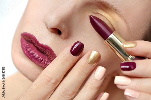 Multi-colored nail design.Trendy Burgundy nail Polish and lip makeup.Glamorous plum Burgundy lipstick.