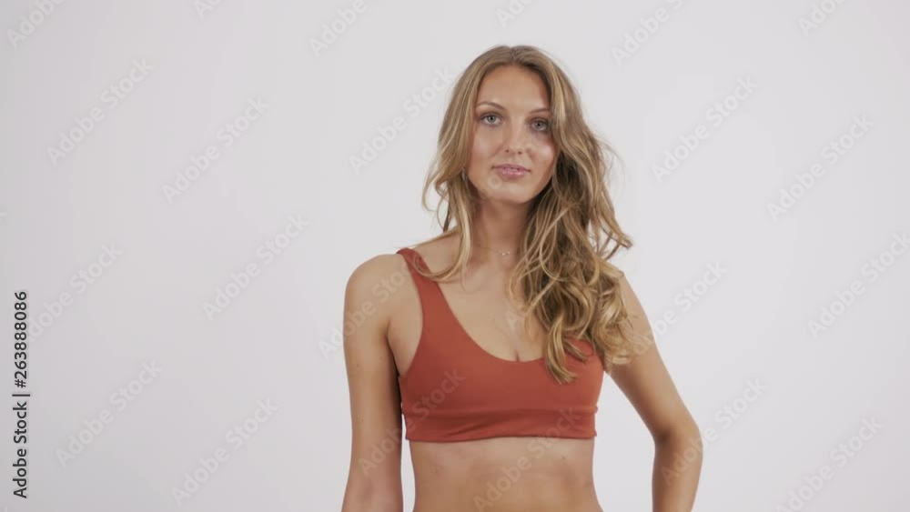 Slim Caucasian model wearing an orange bikini set, posing in a photo studio. Slim Caucasian model wearing an orange bikini set, posing in a photo studio.
