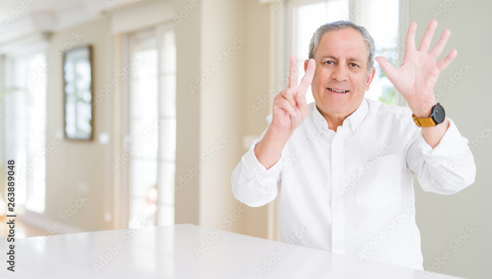 Handsome senior man at home showing and pointing up with fingers number seven while smiling confident and happy.