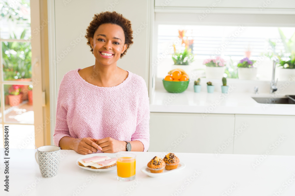 Young african american woman eating breaksfast in the morning at home with a happy and cool smile on face. Lucky person. Young african american woman eating breaksfast in the morning at home with a happy and cool smile on face. Lucky person.