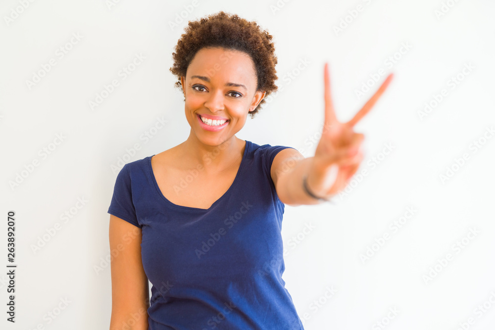 Young beautiful african american woman over white background smiling looking to the camera showing fingers doing victory sign. Number two. Young beautiful african american woman over white background smiling looking to the camera showing fingers doing victory sign. Number two.