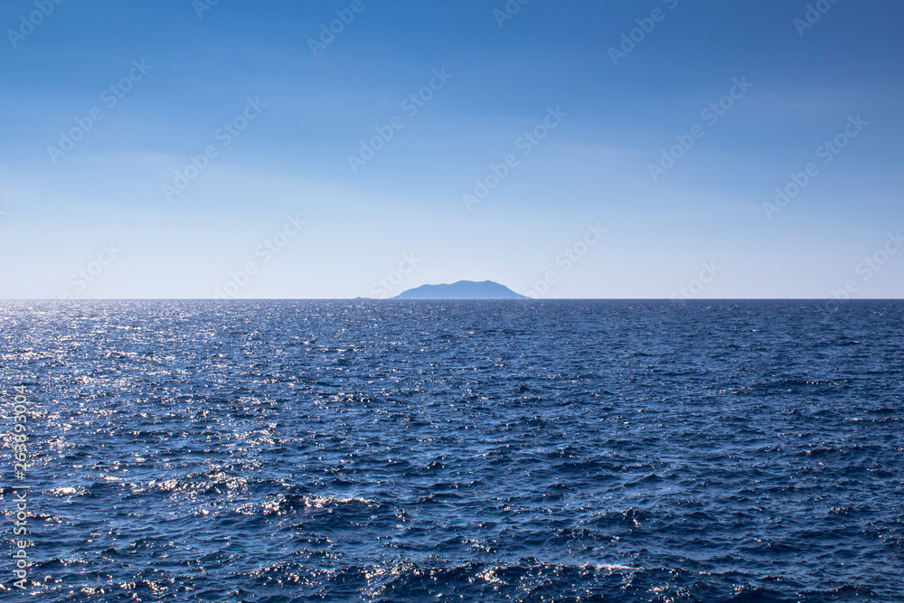 Island on a horizon in still ocean