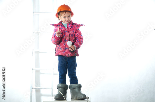 Little girl electrician in a construction helmet with a light bulb.