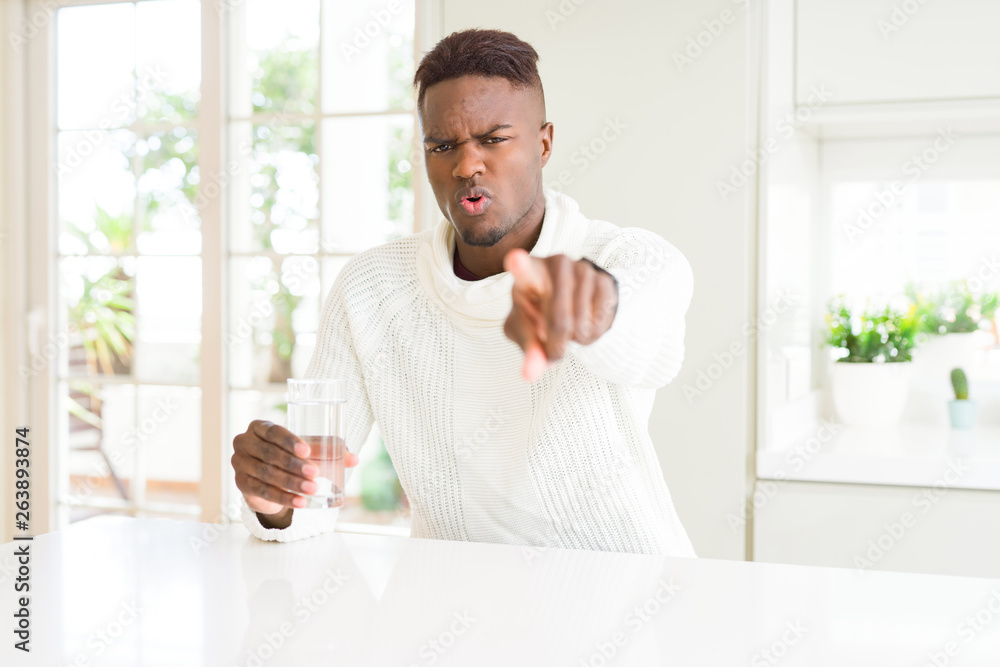African american man driking a fresh glass of water pointing with finger to the camera and to you, hand sign, positive and confident gesture from the front African american man driking a fresh glass of water pointing with finger to the camera and to you, hand sign, positive and confident gesture from the front