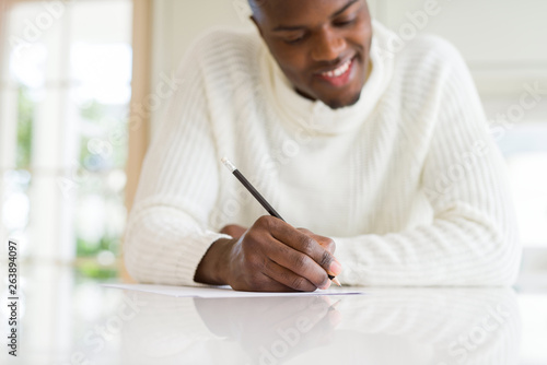 Close up of african man writing a note on a paper smiling confident