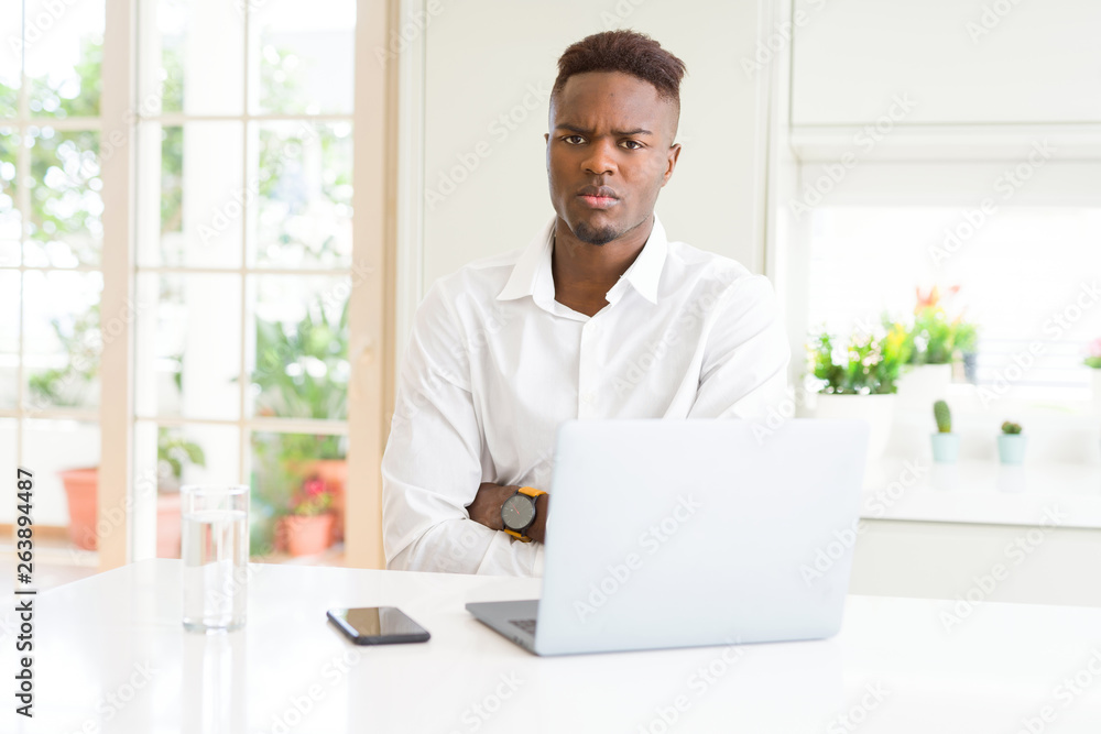 African american business man working using laptop skeptic and nervous, disapproving expression on face with crossed arms. Negative person. African american business man working using laptop skeptic and nervous, disapproving expression on face with crossed arms. Negative person.