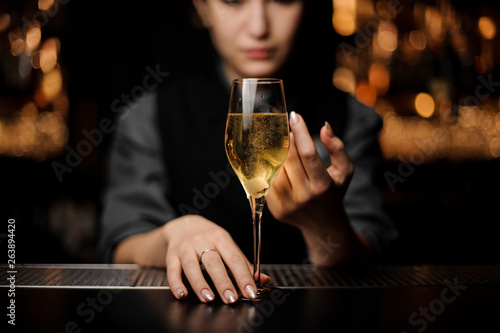 Close-up of the glass with sparkling wine in a bartender's hands