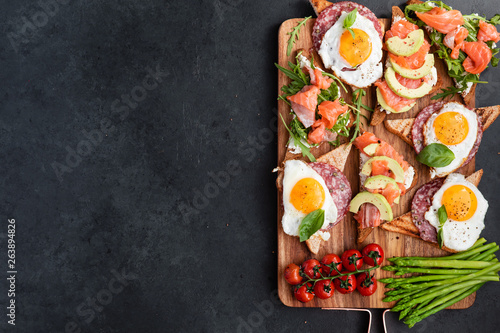 Appetizers table with healthy snacks. Brushetta or sandwich set on the board over black concrete background. Top view, flat lay
