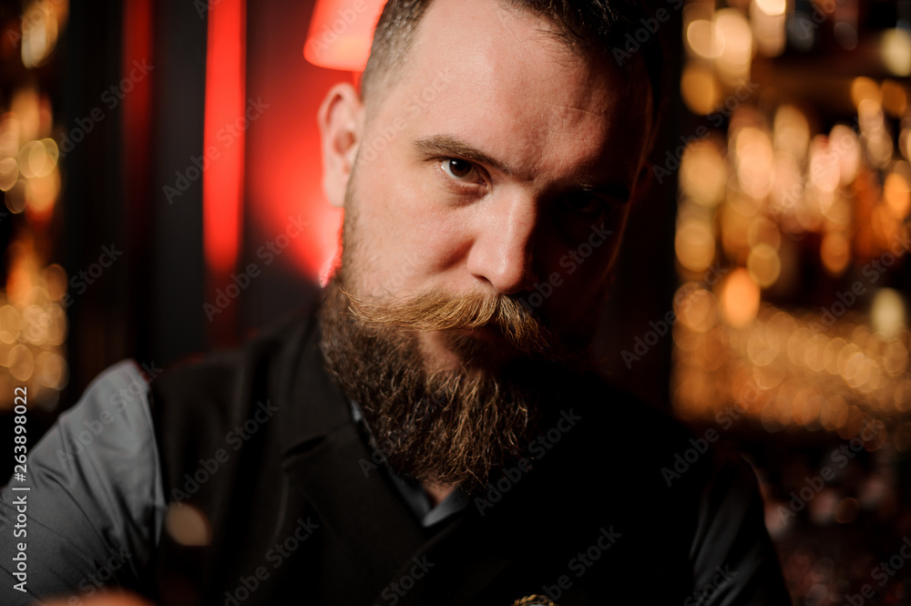 Close-up photo of young male bartender with beard