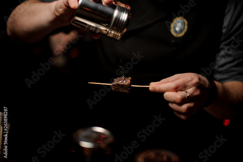 Bartender sprinkles piece of chocolate on a toothpick