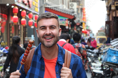 Tourist eating Asian street food on a stick 