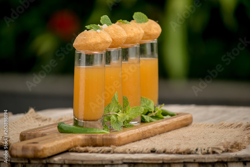 Pani Puri Shots : (a.k.a. golgappa shots or gol gappe shots) are a versatile snack invented in India made of stuffed pani puri (golgappa) placed on top of liquid-filled shot glasses. photo