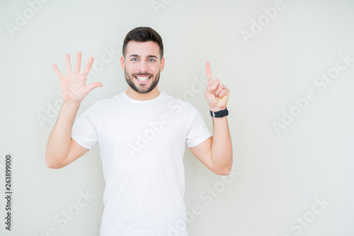 Young handsome man wearing casual white t-shirt over isolated background showing and pointing up with fingers number six while smiling confident and happy. © Krakenimages.com
