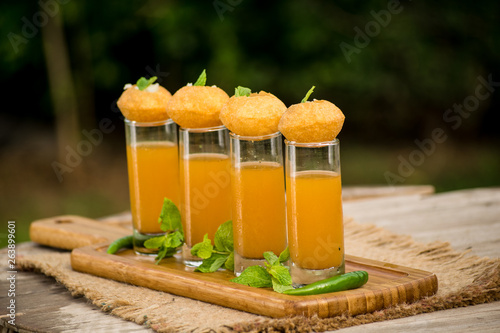 Pani Puri Shots : (a.k.a. golgappa shots or gol gappe shots) are a versatile snack invented in India made of stuffed pani puri (golgappa) placed on top of liquid-filled shot glasses. photo